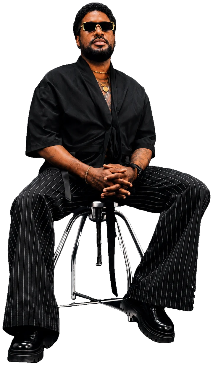 Kelly Silva in a black kimono shirt and pinstripe trousers, seated