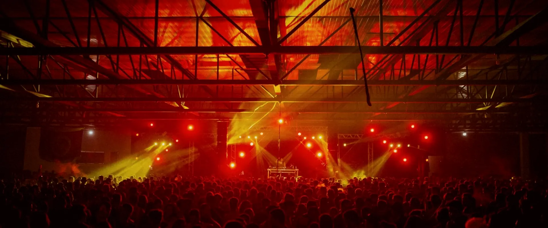 A concert crowd facing a stage washed in red light
